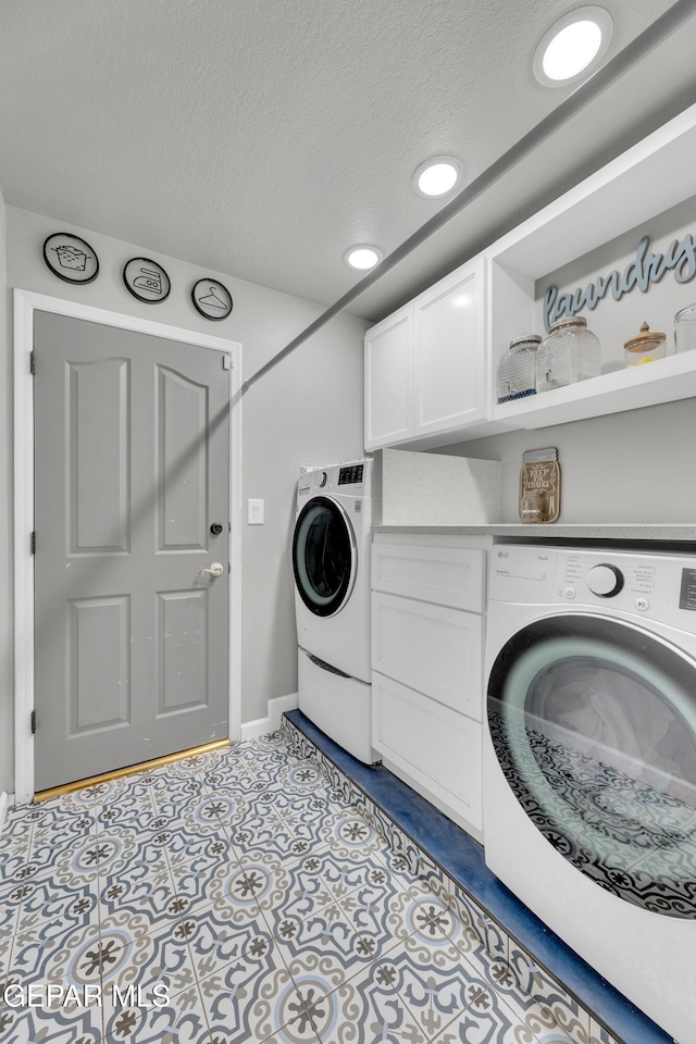 washroom featuring light tile patterned floors, washer / dryer, cabinets, and a textured ceiling