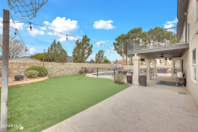 view of yard with ceiling fan, a fenced in pool, a balcony, and a patio area