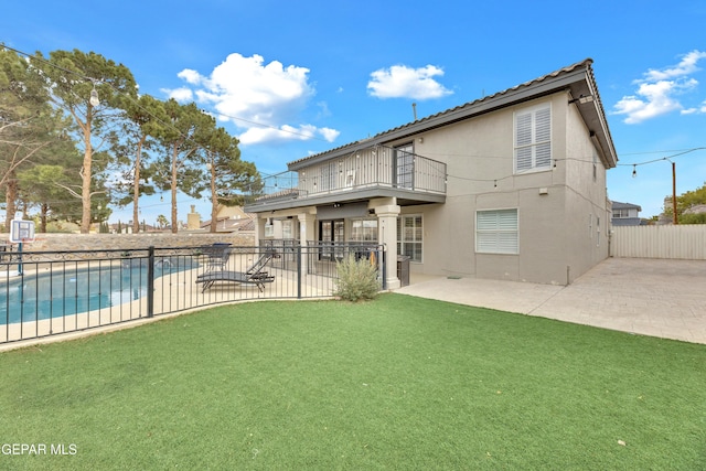 rear view of property with a fenced in pool, a yard, a patio area, and a balcony