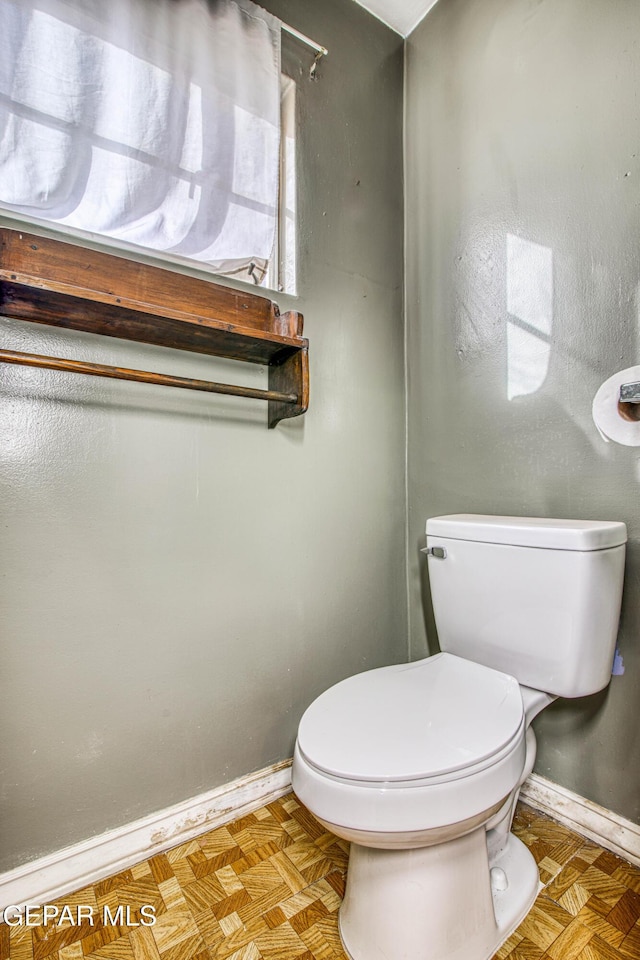 bathroom featuring parquet floors and toilet