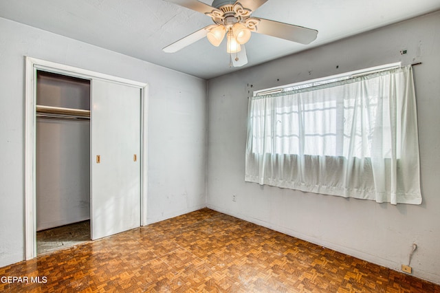 unfurnished bedroom with dark parquet floors, a closet, and ceiling fan