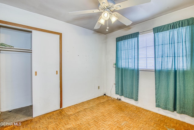 unfurnished bedroom with light parquet floors, ceiling fan, and a closet