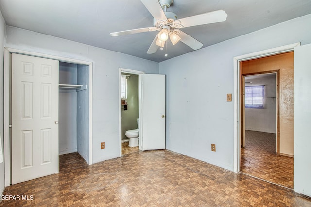 unfurnished bedroom with ceiling fan, connected bathroom, dark parquet floors, and a closet