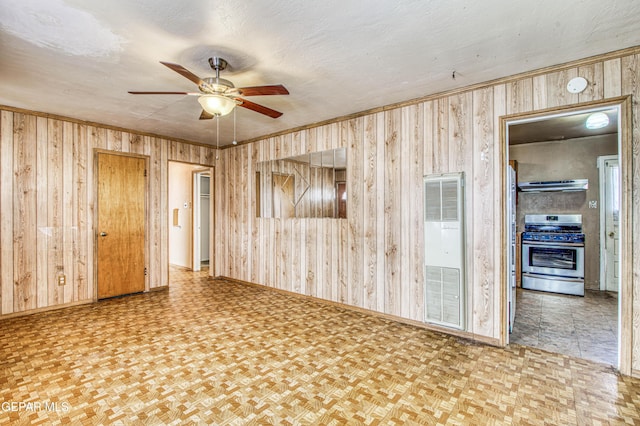 unfurnished room featuring wooden walls, parquet floors, ornamental molding, ceiling fan, and a textured ceiling