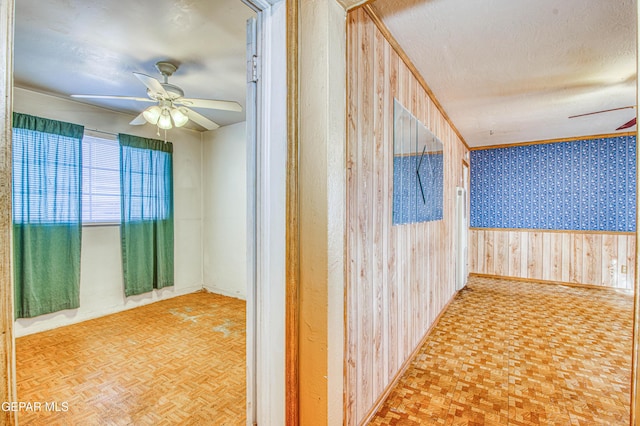 hall with parquet flooring, a textured ceiling, and wood walls