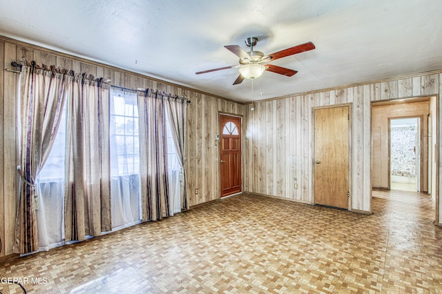 spare room with ceiling fan, parquet flooring, and wooden walls