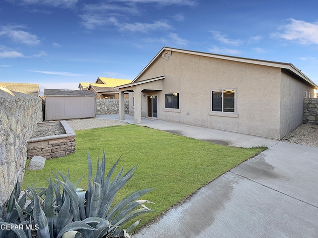 rear view of house with a storage unit, a yard, and a patio