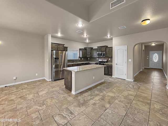 kitchen with a kitchen island, sink, backsplash, stainless steel appliances, and dark brown cabinets