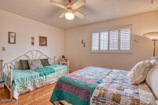 bedroom featuring a textured ceiling, a ceiling fan, and wood finished floors