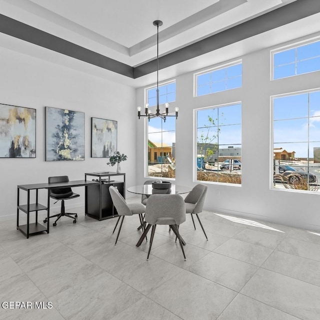 dining area featuring a high ceiling, a raised ceiling, and a chandelier