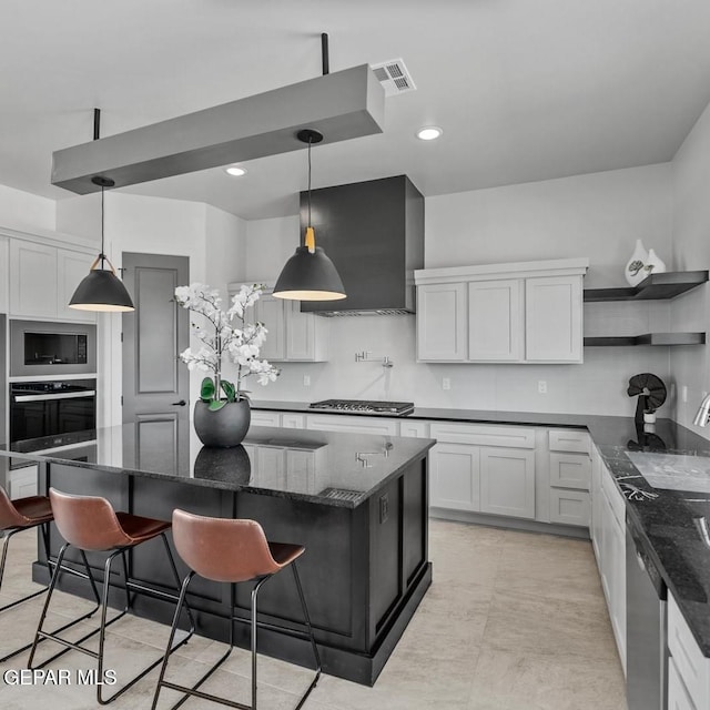 kitchen with a kitchen island, appliances with stainless steel finishes, a breakfast bar area, white cabinets, and hanging light fixtures