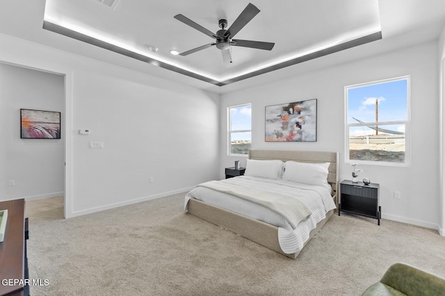 bedroom with a raised ceiling, light carpet, and ceiling fan