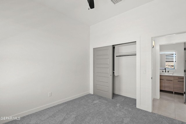 unfurnished bedroom featuring sink, light colored carpet, a closet, and ceiling fan