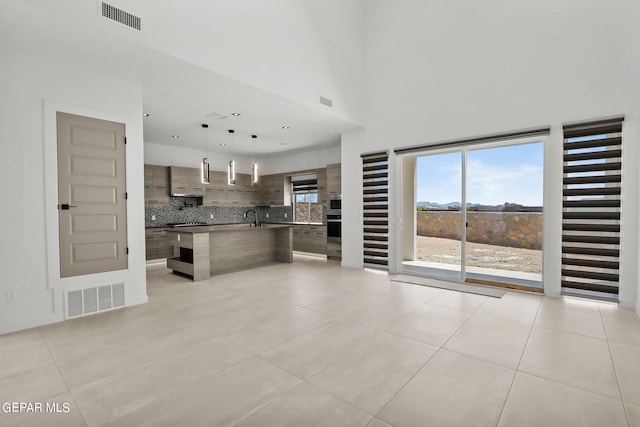 unfurnished living room with sink, a high ceiling, and light tile patterned floors