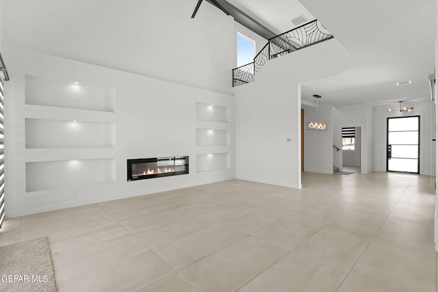 unfurnished living room with a towering ceiling, a wealth of natural light, built in features, and light tile patterned flooring