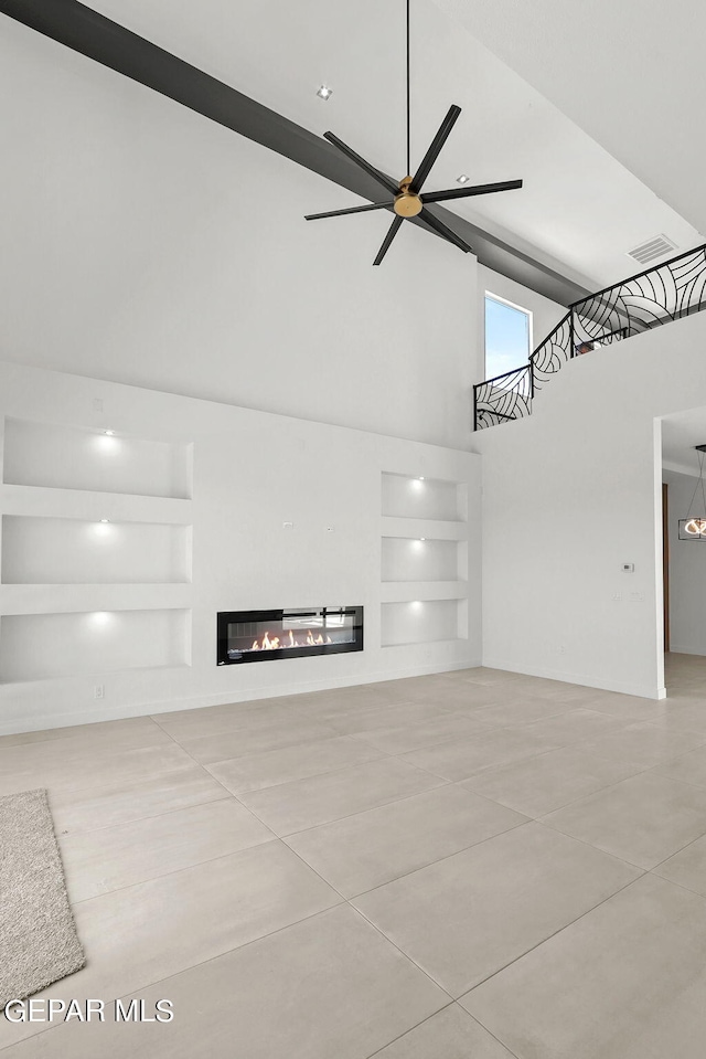 unfurnished living room featuring ceiling fan, built in features, and a high ceiling