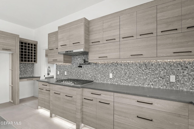 kitchen with tasteful backsplash, sink, stainless steel gas cooktop, and light tile patterned floors