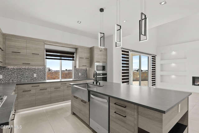 kitchen featuring light tile patterned flooring, sink, appliances with stainless steel finishes, an island with sink, and pendant lighting