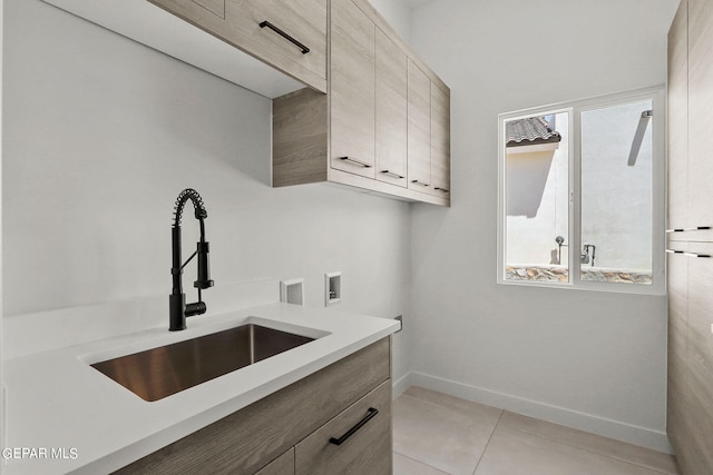 washroom featuring washer hookup, sink, light tile patterned floors, and cabinets