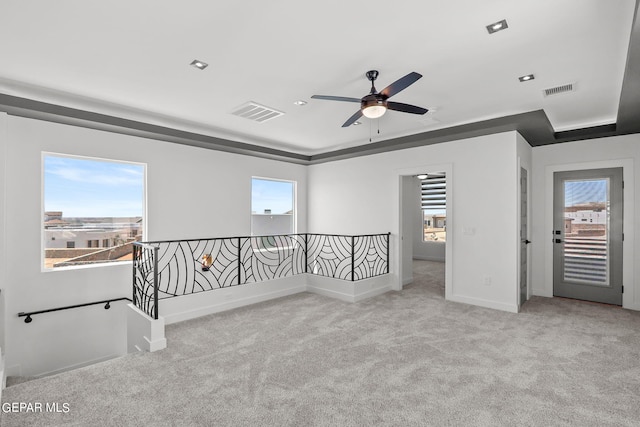 carpeted empty room featuring a raised ceiling and plenty of natural light