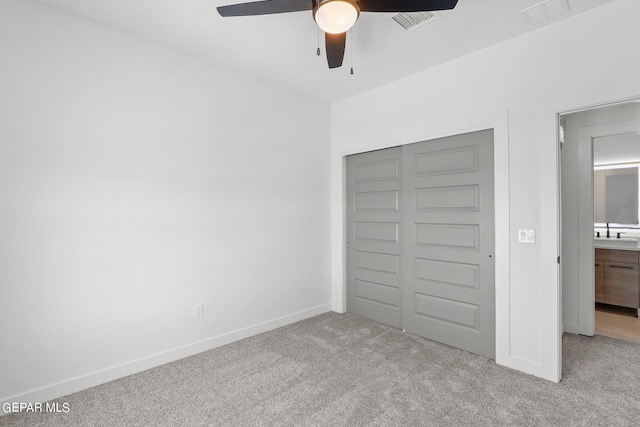 unfurnished bedroom featuring sink, light carpet, ceiling fan, and a closet