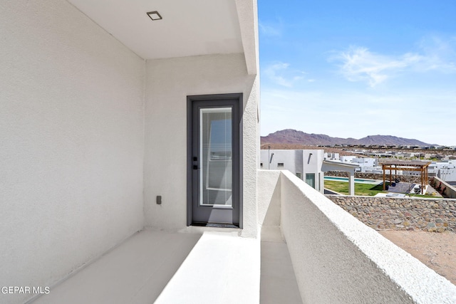 view of exterior entry with a mountain view and a balcony