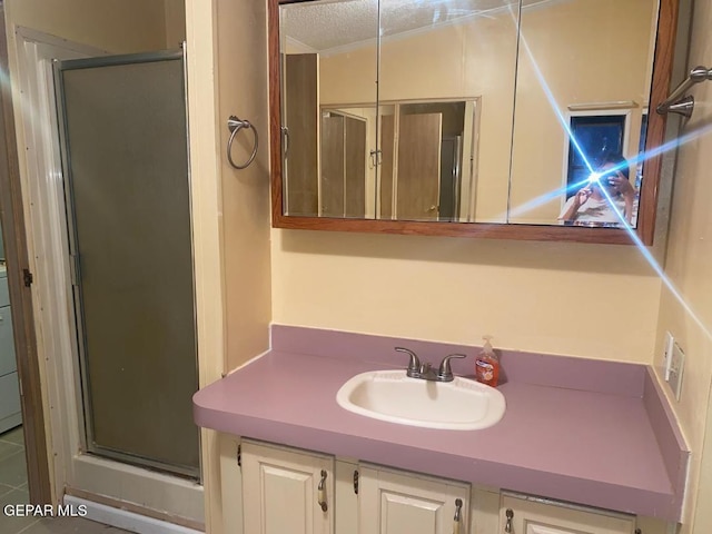 bathroom with walk in shower, vanity, and a textured ceiling