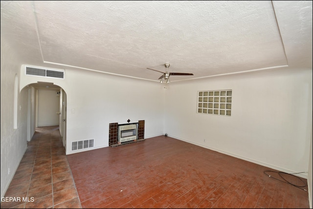 unfurnished living room featuring ceiling fan, a fireplace, dark hardwood / wood-style flooring, and a textured ceiling