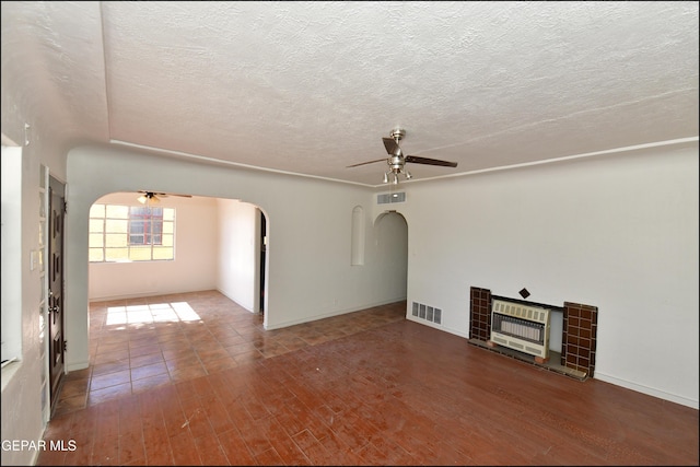 unfurnished living room featuring heating unit, a fireplace, hardwood / wood-style flooring, ceiling fan, and a textured ceiling