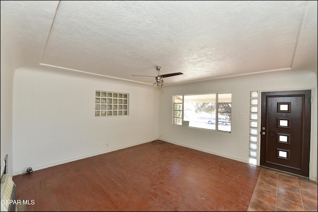 foyer featuring ceiling fan, dark hardwood / wood-style flooring, and a textured ceiling