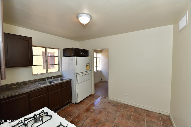 kitchen with dark brown cabinetry, sink, and white fridge with ice dispenser