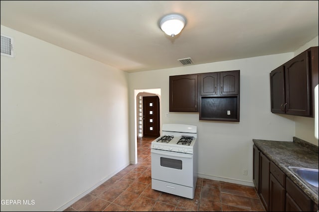 kitchen with white range with gas cooktop and dark brown cabinetry