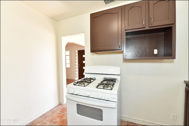 kitchen with white range with gas cooktop, light tile patterned floors, and dark brown cabinetry