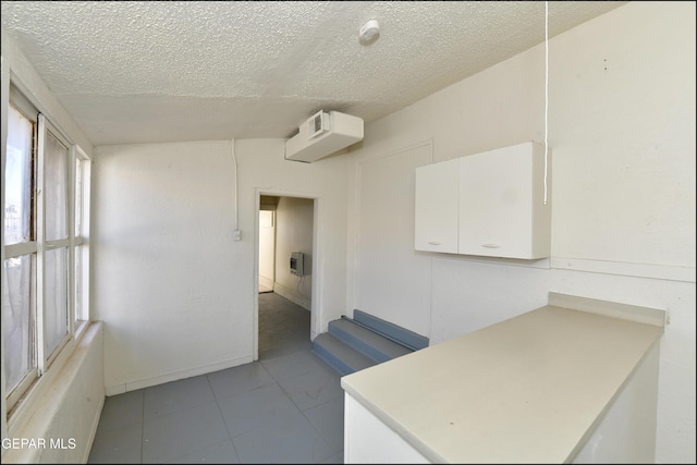 kitchen featuring a textured ceiling and white cabinets