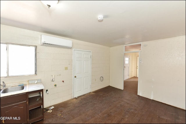 interior space with dark hardwood / wood-style flooring, sink, dark brown cabinets, and a wall mounted AC