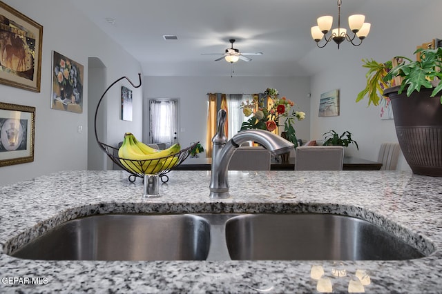 kitchen featuring ceiling fan with notable chandelier, light stone countertops, sink, and hanging light fixtures