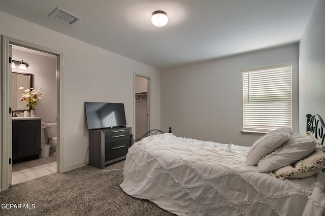 carpeted bedroom with a spacious closet and ensuite bathroom