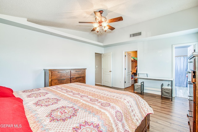 bedroom with hardwood / wood-style flooring, ceiling fan, a spacious closet, and a textured ceiling