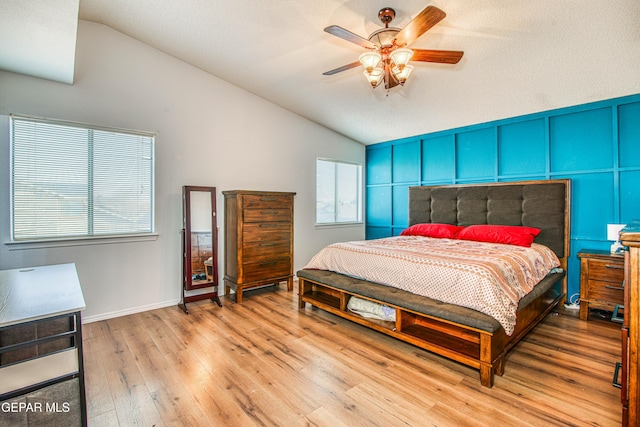 bedroom with ceiling fan, light hardwood / wood-style floors, and vaulted ceiling