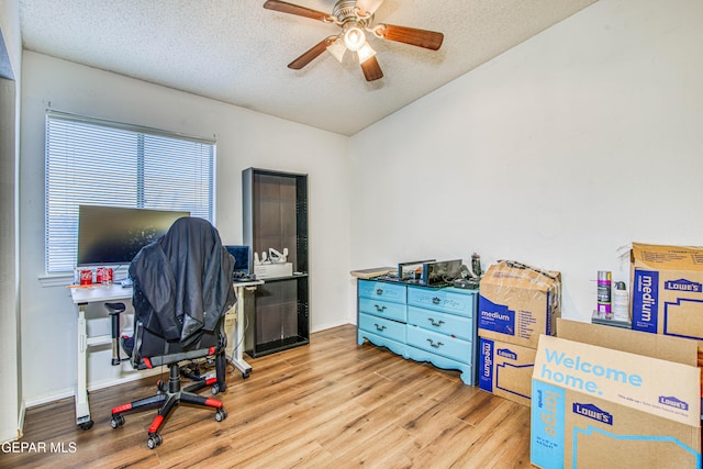 home office with ceiling fan, lofted ceiling, light hardwood / wood-style flooring, and a textured ceiling