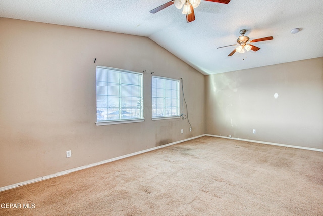 carpeted empty room with vaulted ceiling, ceiling fan, and a textured ceiling