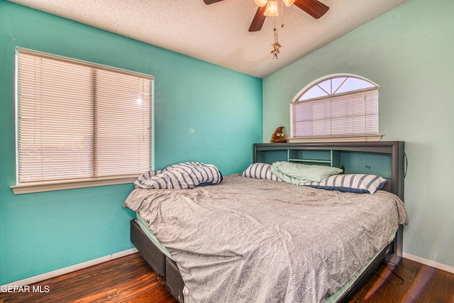 bedroom featuring ceiling fan, dark wood-type flooring, a textured ceiling, and vaulted ceiling