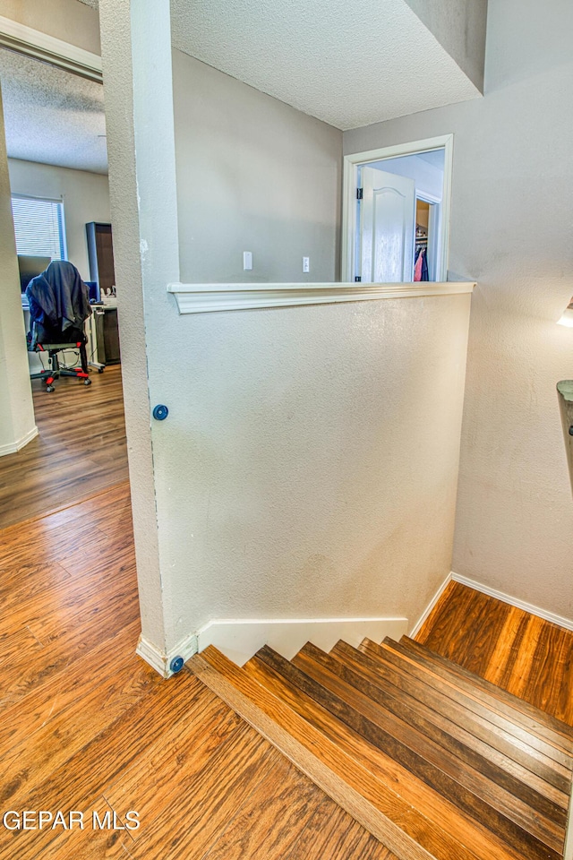 stairs with hardwood / wood-style flooring and a textured ceiling