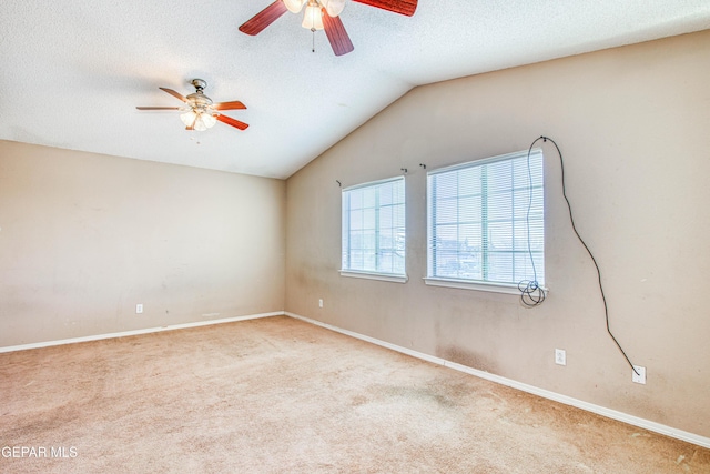 empty room with vaulted ceiling, light carpet, ceiling fan, and a textured ceiling