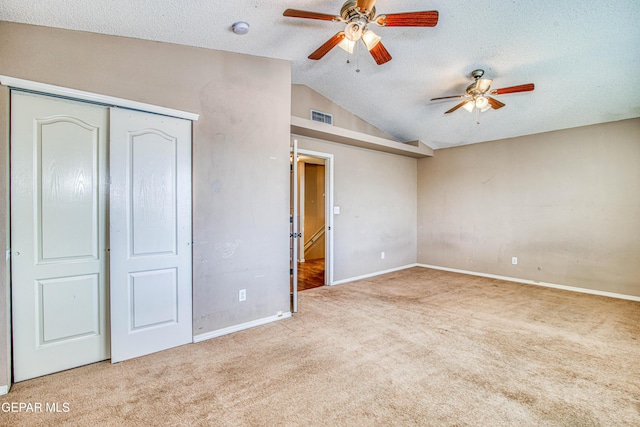 unfurnished bedroom with ceiling fan, lofted ceiling, light carpet, and a textured ceiling