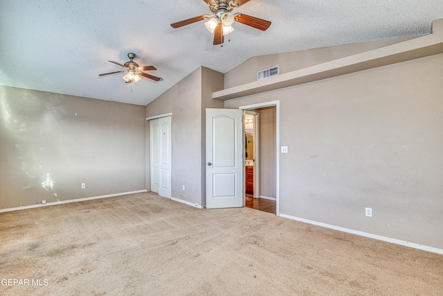 unfurnished bedroom with ceiling fan, carpet floors, a textured ceiling, and vaulted ceiling