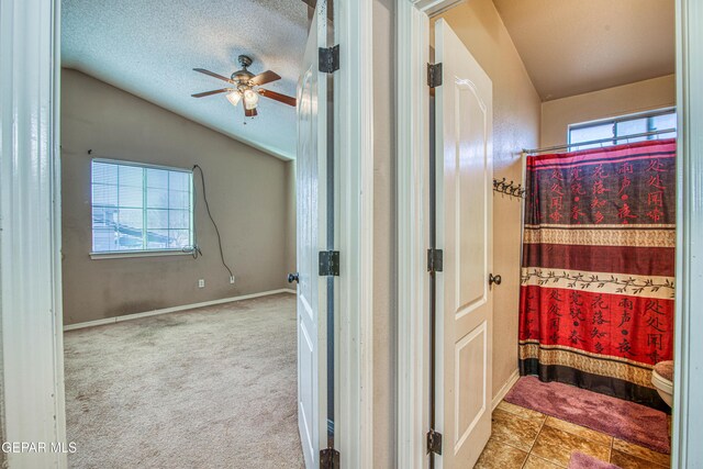 bathroom featuring lofted ceiling, a textured ceiling, toilet, and a healthy amount of sunlight