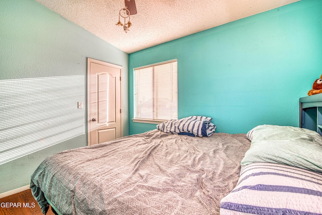 bedroom featuring lofted ceiling, wood-type flooring, and a textured ceiling