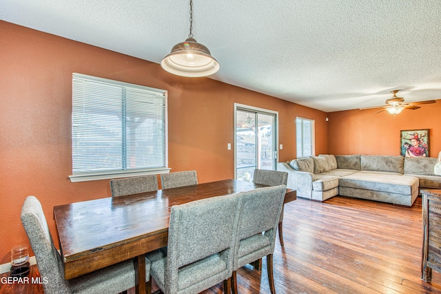 dining space featuring ceiling fan, hardwood / wood-style flooring, and a textured ceiling