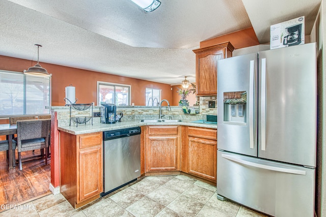 kitchen with sink, hanging light fixtures, kitchen peninsula, and appliances with stainless steel finishes